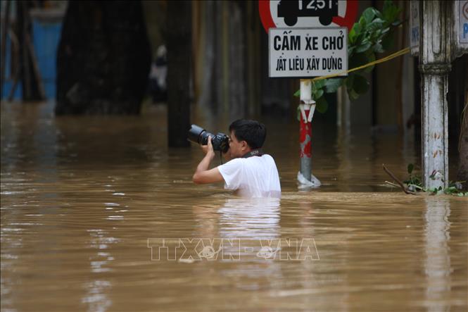 Trong ảnh: Phóng viên Xuân Trường (Ban BT Ảnh) dầm mình trong nước để tác nghiệp về tình hình mưa lũ (tháng 9/2009). Ảnh: TTXVN