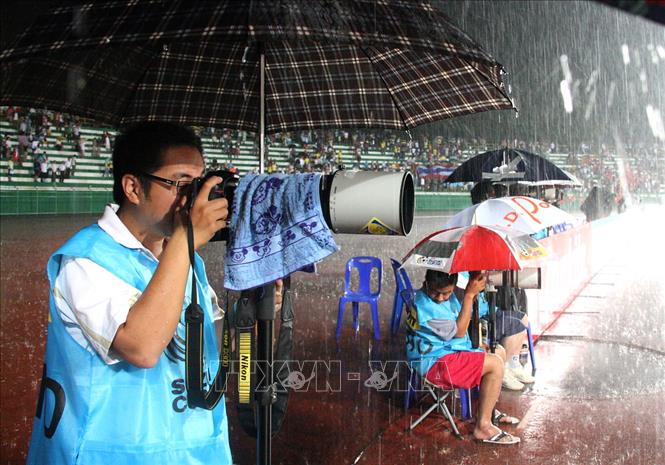 Trong ảnh: Phóng viên Quốc Khánh (Ban BT Ảnh) tác nghiệp dưới trời mưa tại AFF Suzuki Cup 2009 ở Phuket (Thái Lan). Ảnh: TTXVN