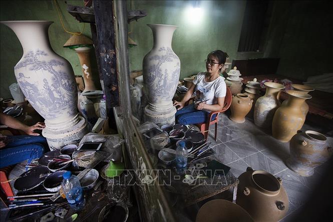 Trong ảnh: Công đoạn tạo hoa văn cho sản phẩm gốm. Để làm ra một sản phẩm gốm trọn vẹn thì sản phẩm gốm phải qua các khâu chọn, xử lý và pha chế đất, tạo dáng, tạo hoa văn, phủ men, và cuối cùng là nung sản phẩm. Kinh nghiệm truyền đời của dân làng gốm Bát Tràng là 