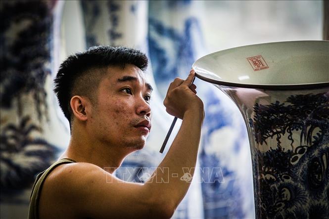 Trong ảnh: Những nghệ nhân trẻ tuổi đang tiếp bước thế hệ đi trước miệt mài sáng tạo làm ra các sản phẩm gốm với nhiều công phu. Phải trải qua các khâu chọn, xử lý và pha chế đất, tạo dáng, tạo hoa văn, phủ men và cuối cùng là nung sản phẩm.  Ảnh: Trọng Đạt - TTXVN