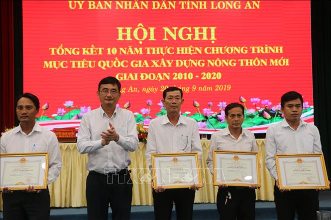 Trong ảnh: Phó Chủ tịch UBND tỉnh Long An Phạm Văn Cảnh, tặng bằng khen cho các tập thể đạt thành trong phong trào thi đua xây dựng nông thôn mới. Ảnh: Thanh Bình- TTXVN

