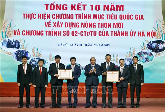Trong ảnh: Thủ tướng Nguyễn Xuân Phúc trao bằng công nhận đạt chuẩn nông thôn mới năm 2019 cho huyện Quốc Oai và huyện Gia Lâm. Ảnh: Thống Nhất - TTXVN