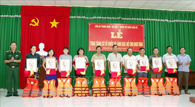 Trong ảnh: Lãnh đạo BĐBP Sóc Trăng trao tặng cờ và ảnh bác Hồ cho ngư dân vùng ven biển Sóc Trăng. Ảnh: Trung Hiếu-TTXVN
