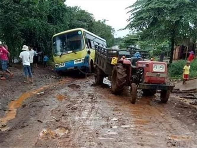  Trong ảnh: Xe khách trở học sinh bị sa lầy phải dùng xe công nông để kéo đi. Ảnh: Dương Chí Tưởng-TTXVN