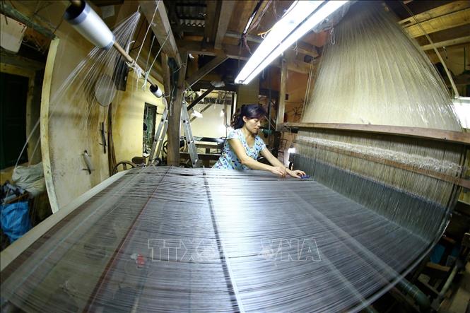 Trong ảnh: Làng lụa hiện có gần 800 hộ dân làm nghề, chiếm gần 60% trên tổng số hộ sinh sống tại đây. Trong nhiều gia đình, khung dệt cổ vẫn được giữ lại, xen lẫn với các khung dệt cơ khí hiện đại. Ảnh: Minh Quyết – TTXVN