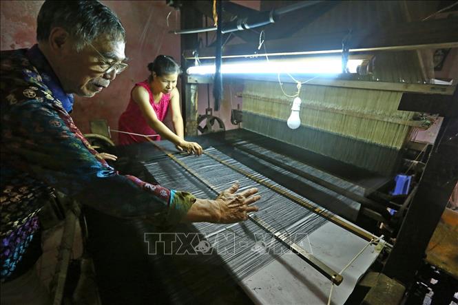 Trong ảnh: Nghệ nhân Đỗ Quang Hùng thường xuyên trao đổi, hướng dẫn những người làm nghề cách làm và tạo ra sản phẩm lụa tốt nhất. Ảnh: Minh Quyết – TTXVN