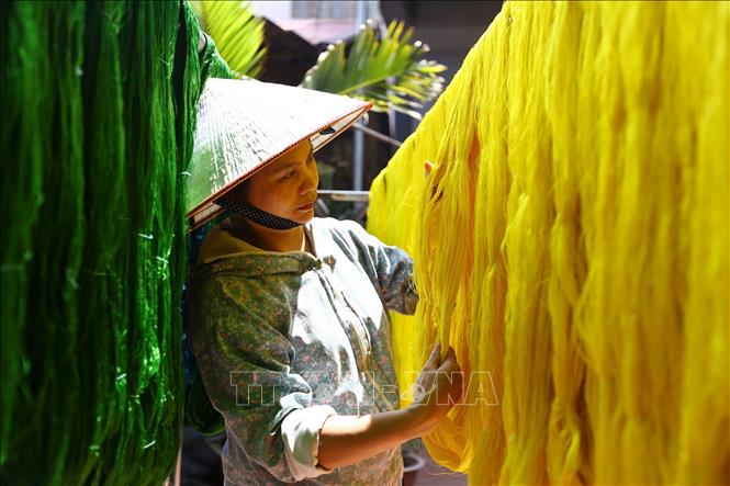 Trong ảnh: Phơi tơ sau khi đã được nhuộm màu tại xưởng dệt của gia đình nghệ nhân Nguyễn Anh Sơn. Không phải loại tơ nào cũng đem nhuộm mà có loại để trắng tinh khiết, ngả vàng ngà như lụa nõn; có loại được nhuộm màu ngay từ khâu sợi như gấm, vóc. Ảnh: Minh Quyết – TTXVN