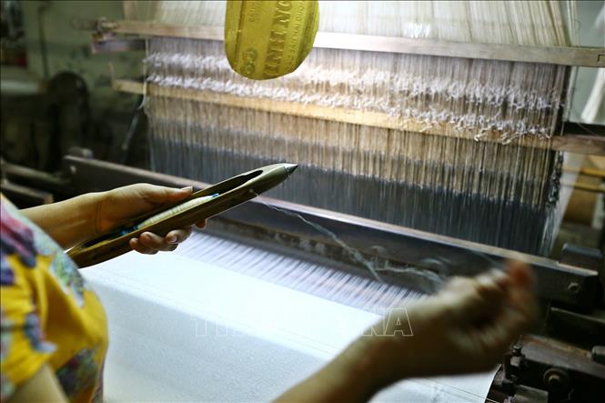 Trong ảnh: Tra suốt vào thoi để chuẩn bị dệt. Ảnh: Minh Quyết – TTXVN