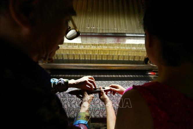 Trong ảnh: Nghệ nhân Đỗ Quang Hùng thường xuyên trao đổi, hướng dẫn cho những người làm nghề cách làm và tạo ra sản phẩm lụa tốt nhất. Ảnh: Minh Quyết – TTXVN