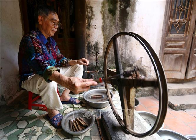 Trong ảnh: Nghệ nhân Đỗ Quang Hùng, 77 tuổi, đã nghiên cứu và làm ra sản phẩm lụa không phai, các dải màu, hoa văn trên lụa được ông pha trộn tơ bằng guồng thủ công. Ảnh: Minh Quyết – TTXVN