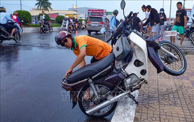 Người dân khắc phục sự cố xe máy khi đi qua đoạn ngập sâu. Ảnh: Thanh Liêm - TTXVN