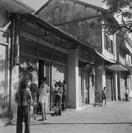 Trong ảnh: Từ sáng sớm, người dân Hà Nội treo cờ, khẩu hiệu trước cửa nhà, đón chào bộ đội về giải phóng Thủ đô. Ảnh: Tư liệu TTXVN