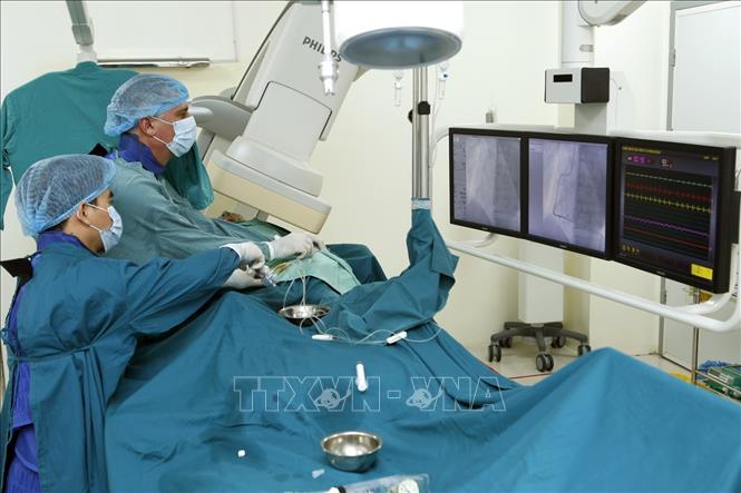 Trong ảnh: Giáo sư Piter Martinez Beniter (phía trong), chuyên gia Cu Ba cùng với các bác sĩ bệnh viện Hữu nghị Việt Nam Cuba  Đồng Hới đã thực hiện gần 300 ca can thiệp tim mạch trong hơn 1 năm qua. Ảnh: Dương Ngọc – TTXVN