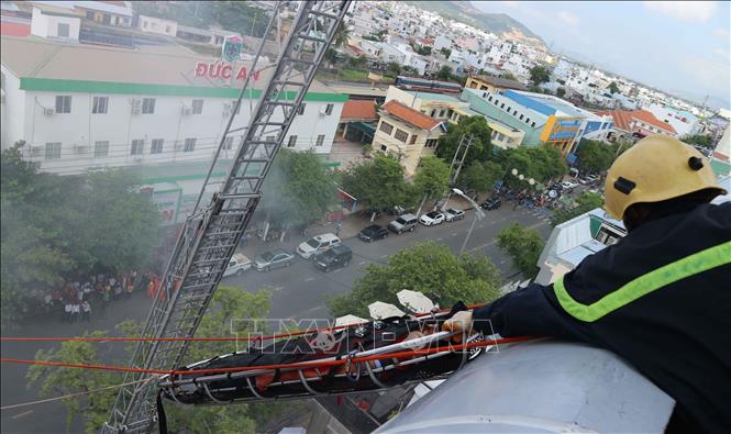 Trong ảnh: Lực lượng cứu hộ đưa người bị thương từ trên tầng thượng xuống đất bằng phương pháp dùng “máng trượt di động”. Ảnh: Nguyễn Dũng – TTXVN