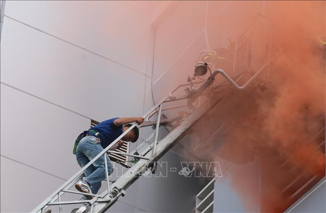 Trong ảnh: Nạn nhân thoát khỏi đám cháy từ xe thang chuyên dụng của lực lượng phòng cháy chữa cháy. Ảnh: Nguyễn Dũng – TTXVN