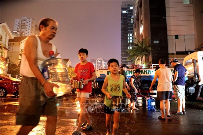 Trong ảnh: Người dân khu đô thị Hapulico (Thanh Xuân Trung) phải mang bình, xô, chậu, thậm chí cả những chiếc chai nhỏ ra xếp hàng chờ hứng nước sạch lúc nửa đêm. Ảnh: Thành Đạt - TTXVN