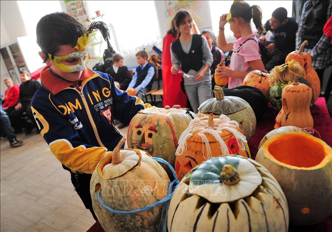 Trong ảnh: Các em học sinh giới thiệu các tác phẩm chạm khắc bí ngô chào đón Lễ Halloween ở Bucharest. Ảnh: AFP/TTXVN