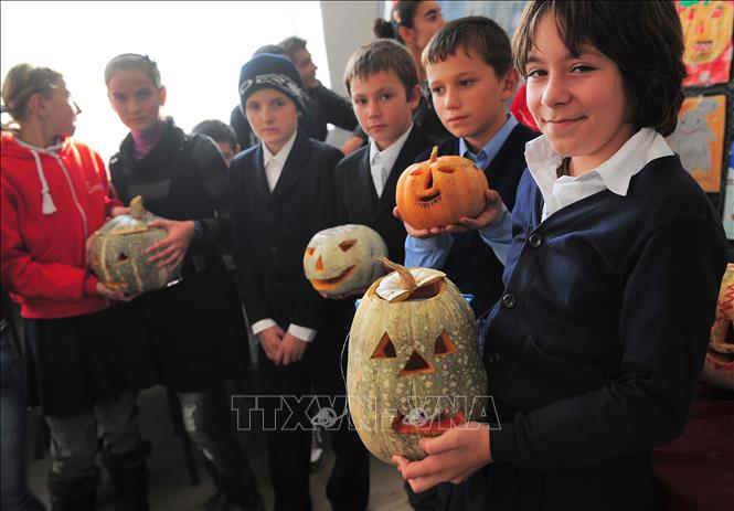 Trong ảnh: Các em học sinh giới thiệu các tác phẩm chạm khắc bí ngô chào đón Lễ Halloween ở Bucharest. Ảnh: AFP/TTXVN