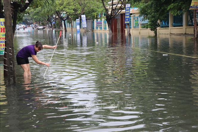 Trong ảnh: Người dân quận Thanh Khê khơi thông các miệng cống thoát nước để giúp thoát nước mưa nhanh chóng tại khu bị ngập. Ảnh: Trần Lê Lâm - TTXVN 