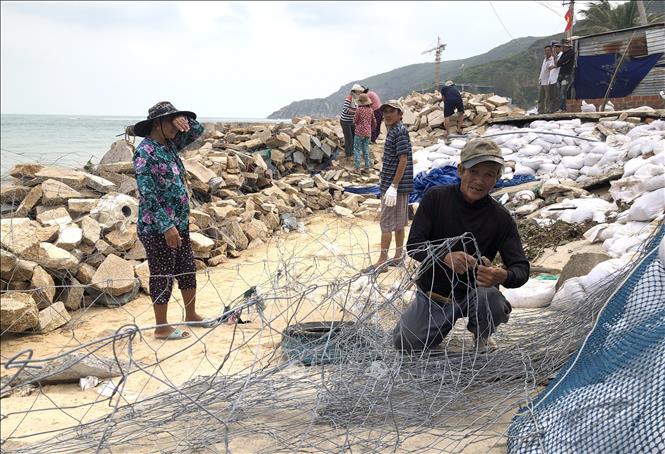 Người dân làng Hải Nam, xã Nhơn Hải, thành phố Quy Nhơn buộc rọ thép, đắp kè đá ngăn sóng biển. Ảnh: Nguyên Linh - TTXVN