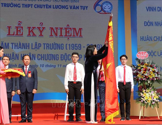 Trong ảnh: Phó Chủ tịch nước Đặng Thị Ngọc Thịnh gắn Huân chương Độc lập hạng Nhì lên cờ truyền thống của nhà trường. Ảnh: Đức Phương - TTXVN