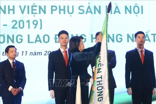 Trong ảnh: Phó Chủ tịch nước Đặng Thị Ngọc Thịnh gắn Huân chương Lao động hạng Nhất của Chủ tịch nước lên lá cờ truyền thống của Bệnh viện Phụ sản Hà Nội. Ảnh: Minh Quyết - TTXVN