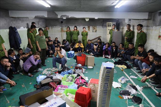 Trong ảnh: Các đối tượng liên quan cùng tang vật bị Công an bắt giữ tại sới bạc. Ảnh: TTXVN phát