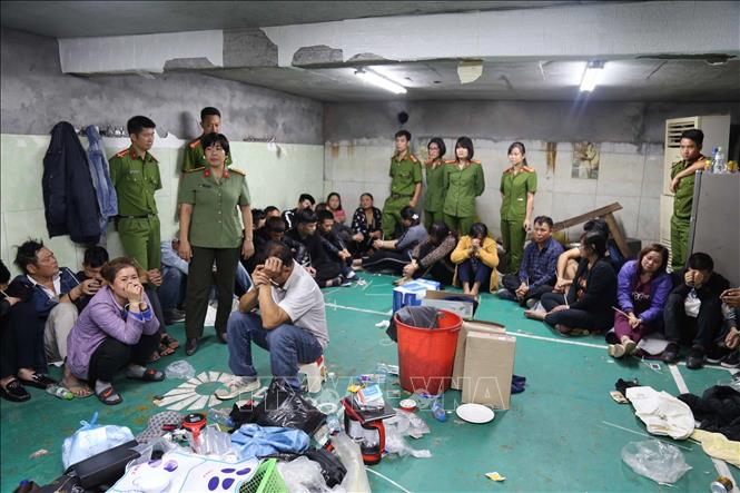 Trong ảnh: Các đối tượng liên quan cùng tang vật bị công an bắt giữ tại sới bạc. Ảnh: TTXVN phát