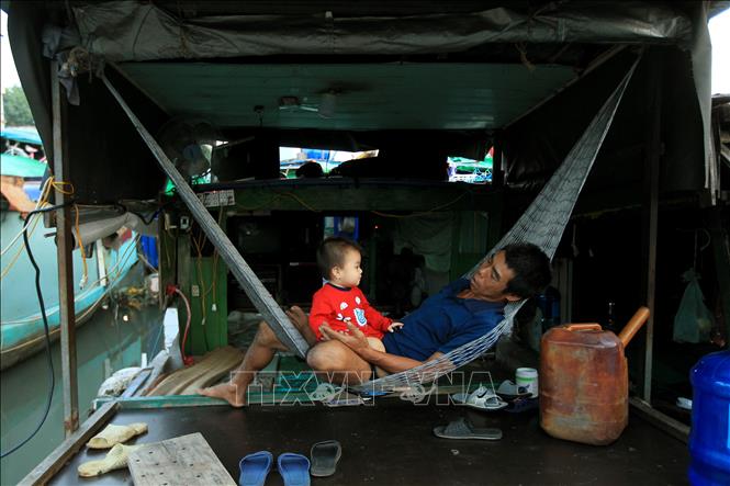 Trong ảnh: Người đàn ông phải bỏ việc để ở nhà chăm cháu vì không có tiền cho cháu đi học. Ảnh: An Đăng - TTXVN
