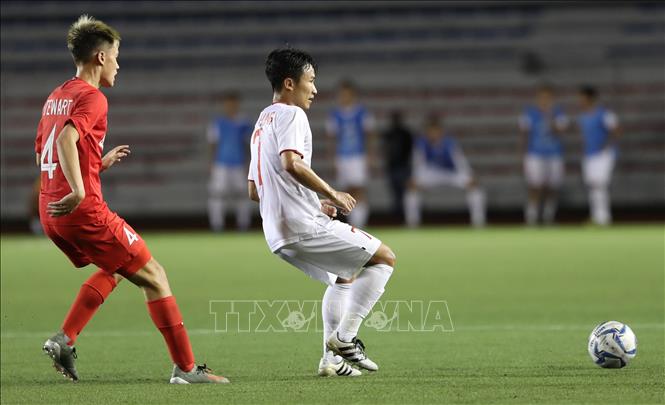 Trong ảnh: Tiền vệ Việt Hưng che bóng trước hậu vệ Singapore