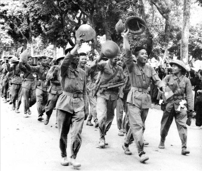 7. Sáng 10/10/1954, các đơn vị của Đại đoàn Quân Tiên Phong-Sư đoàn 308 chia làm nhiều cánh mở cuộc hành quân lịch sử tiến vào Hà Nội trong rừng cờ hoa cùng niềm vui hân hoan của hai mươi vạn người dân Thủ đô tràn ra đường chào đón đoàn quân chiến thắng. Ảnh: Tư liệu TTXVN