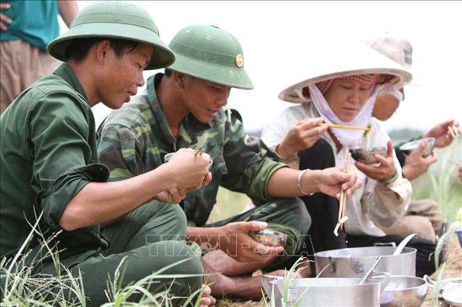 24. Chủ tịch Hồ Chí Minh đã khẳng định: “Có dân là có tất cả”, “Quân dân một lòng, thì kháng chiến ắt thắng lợi, kiến quốc ắt thành công”. Trong ảnh: Bữa cơm của bộ đội và nhân dân  trong ngày gặt lúa chạy lũ. Ảnh: Tràng Dương - TTXVN