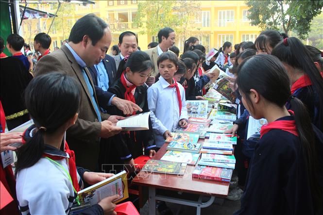 Các đại biểu và học sinh tham quan, trải nghiệm các tiện ích của xe thư viện lưu động. Ảnh: Thu Hằng - TTXVN