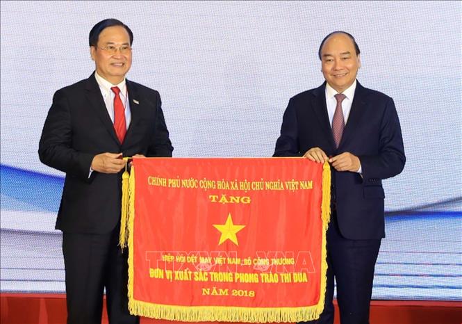 Trong ảnh: Thủ tướng Nguyễn Xuân Phúc tặng Cờ Thi đua của Chính phủ cho Hiệp hội dệt may Việt Nam. Ảnh: Thống Nhất – TTXVN
