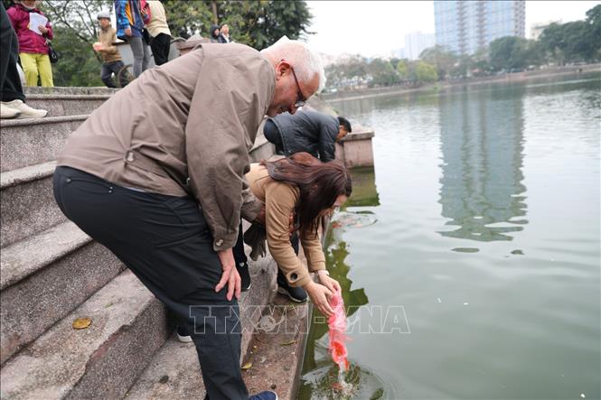 Trong ảnh: Người nước ngoài háo hức với phong tục thả cá chép để tiễn đưa ông Táo về trời. Ảnh: Thành Đạt - TTXVN