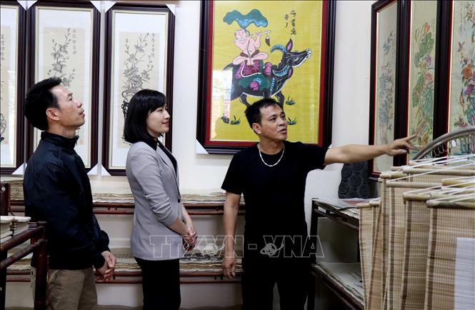 Trong ảnh: Người dân làng Đông Hồ, xã Song Hồ (Thuận Thành, Bắc Ninh) giới thiệu cho du khách về dòng tranh Đông Hồ. Ảnh: Đinh Văn Nhiều - TTXVN