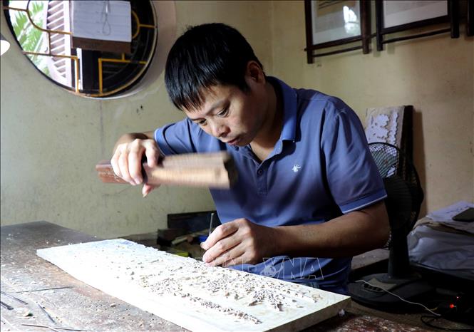 Trong ảnh: Đục nét để in tranh. Ảnh: Đinh Văn Nhiều - TTXVN