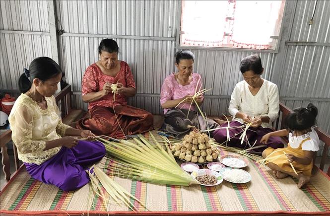 Trong ảnh: Bà Neáng Phương (thứ 2 phải qua) đang hướng dẫn các mẹ, các chị trong xã Ô Lâm cách gói bánh phối trộn các nguyên liệu chuẩn bị gói bánh Kà tum. Ảnh: Công Mạo-TTXVN