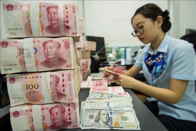 Trong ảnh: Kiểm đồng 100 Nhân dân tệ tại ngân hàng ở tỉnh Giang Tô, Trung Quốc. Ảnh: AFP/TTXVN