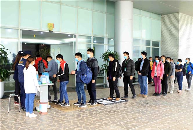 Trong ảnh: Tất cả công nhân, cán bộ, khách hàng đến làm việc tại Công ty TNHH Compal Việt Nam  trong khu công nghiệp Bá Thiện 1 (huyện Bình Xuyên) đều đeo khẩu trang mới, đi qua khay dung dịch khử khuẩn, sát khuẩn tay và đo nhiệt độ để phòng chống dịch COVID-19. Ảnh: Hoàng Hùng - TTXVN