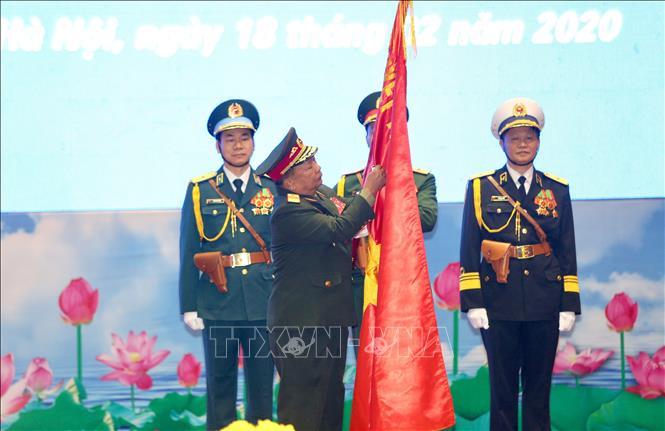 Trong ảnh: Đại tướng Chansamone Chanyalath, Bộ trưởng Bộ Quốc phòng CHDCND Lào gắn Huân chương Tự do hạng Nhất lên cờ truyền thống của Quân đội nhân dân Việt Nam. Ảnh: Dương Giang - TTXVN