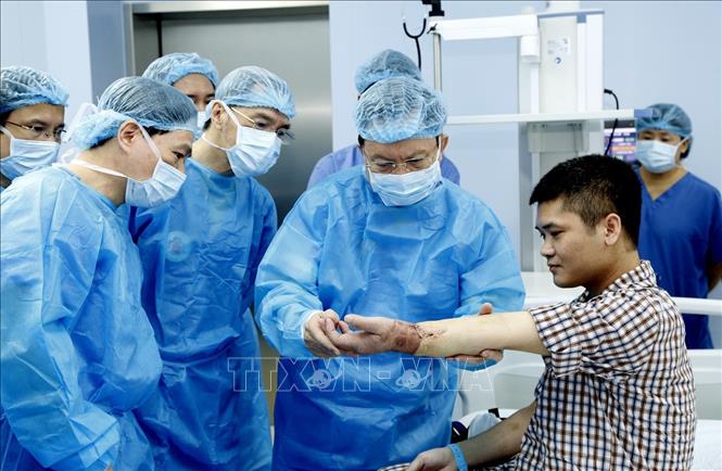 Trong ảnh: Trung tướng, GS,TS, Thầy thuốc nhân dân Mai Hồng Bàng, Giám đốc bệnh viện Trung ương Quân đội 108 kiểm tra chức năng vận động của bệnh nhân sau ca ghép. Ảnh: TTXVN phát