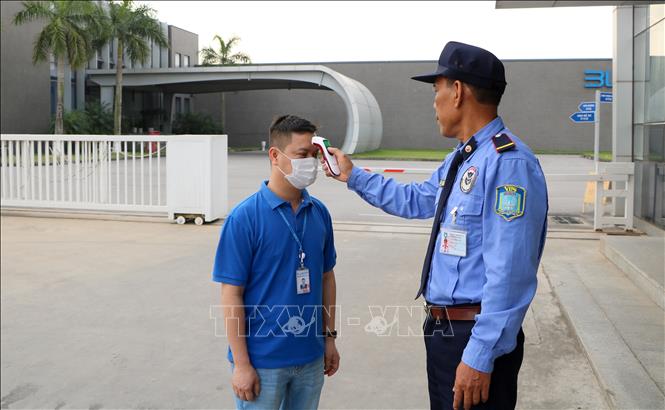 Trong ảnh: Người lao động tại Công ty TNHH Bluecom Vina kiểm tra thân nhiệt trước khi vào công ty làm việc. Ảnh: Minh Thu - TTXVN