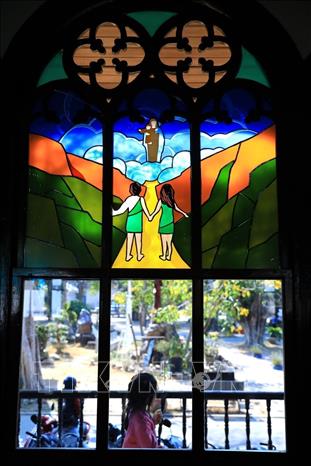 Photo: The stained glass painting on the door frame inscribed with historical references from the Bible brilliantly lights up the magnificent cathedral. VNA Photo: Thành Đạt