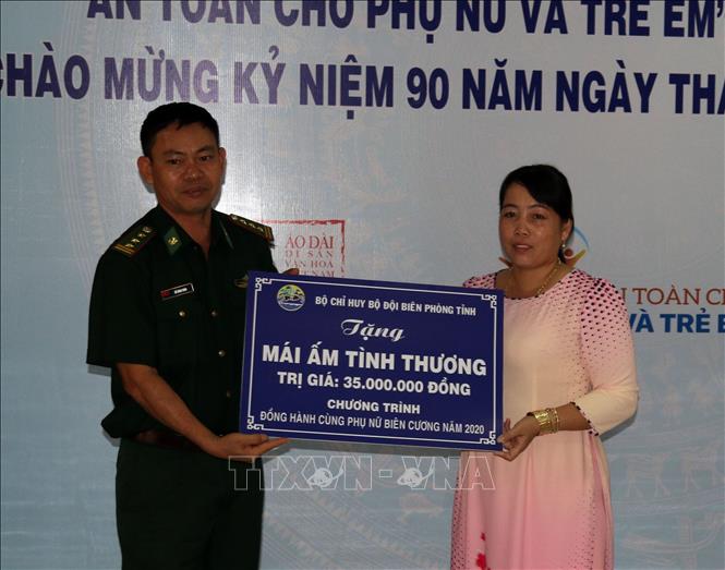 Đại diện Bộ đội Biên phòng Kiên Giang tặng bảng tượng trưng nhà mái ấm tình thương cho phụ nữ nghèo 
Ảnh: Lê Sen - TTXVN