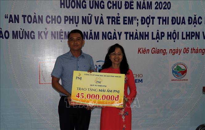 Đại diện Công ty Cổ phần Đá quí Phú Nhuận tặng bảng tượng trưng mái ấm PNJ cho phụ nữ nghèo .
Ảnh: Lê Sen - TTXVN
