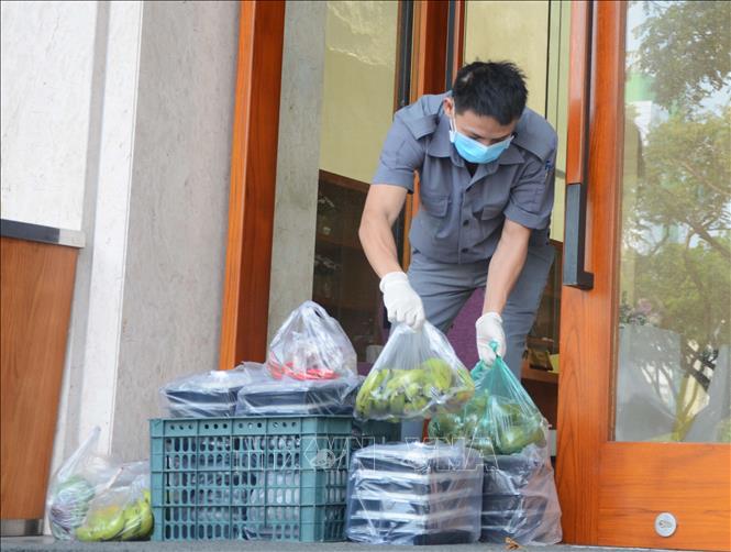 Trong ảnh: Người được cách ly tại khách sạn Vanda tiếp nhận cơm do lực lượng công an chuyển đến. Ảnh: Văn Dũng - TTXVN