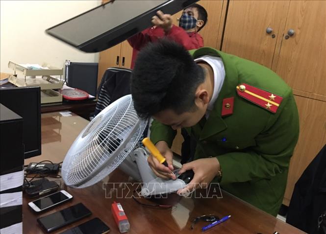 Trong ảnh: Cảnh sát kiểm tra các thiết bị có lắp camera siêu nhỏ của các đối tượng tại cơ quan công an. Ảnh: Doãn Tấn - TTXVN