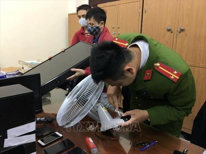 Trong ảnh: Cảnh sát kiểm tra các thiết bị có lắp camera siêu nhỏ của các đối tượng tại cơ quan công an. Ảnh: Doãn Tấn - TTXVN