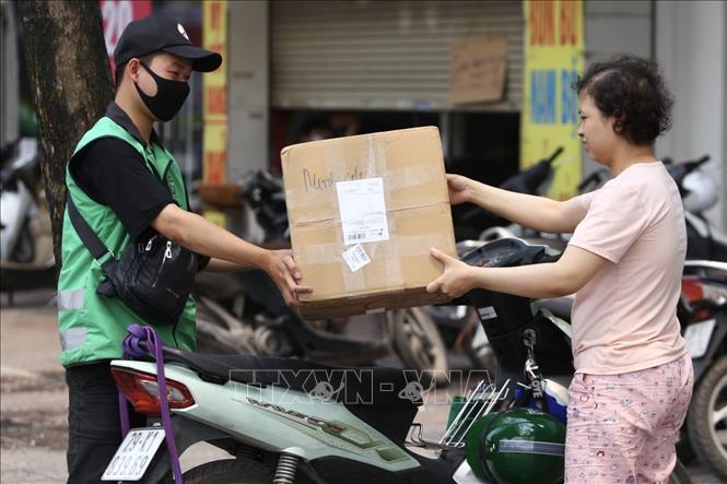 Trong ảnh: Shipper giao hàng cho khách. Ảnh: Minh Quyết - TTXVN